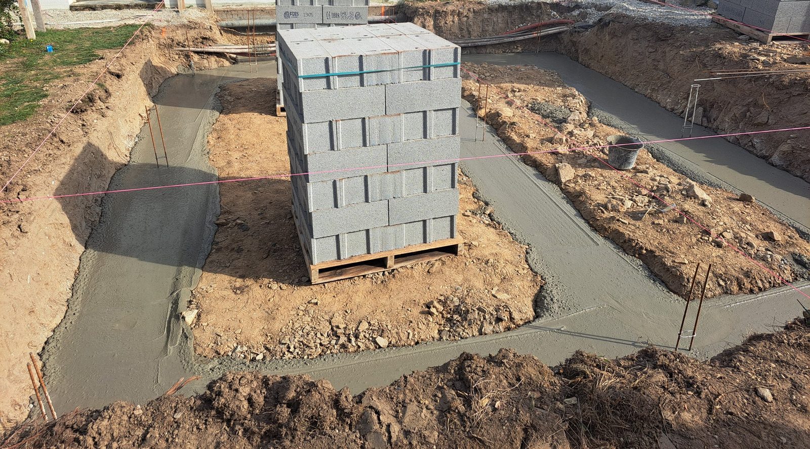 Semelles filantes coulées avec attentes, palettes de blocs béton pour l'élévation