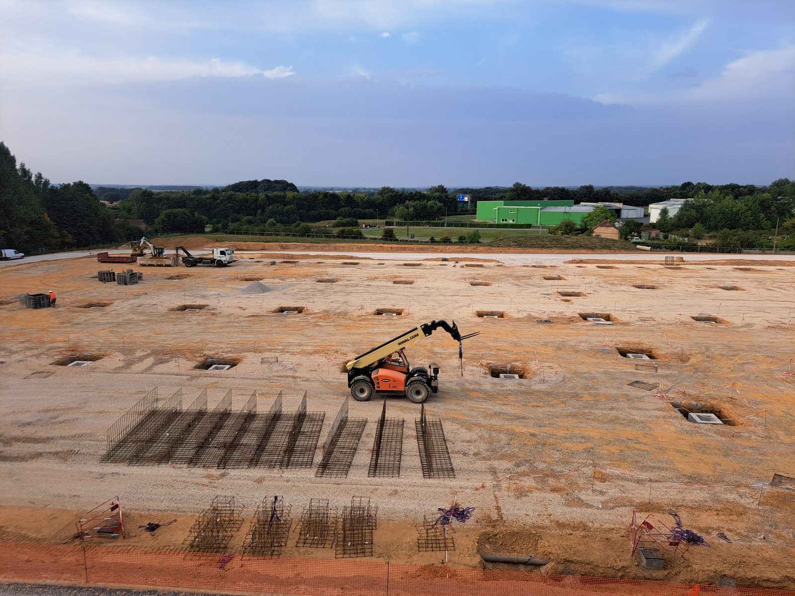 Chantier de bâtiment industriel : fouilles des massifs de fondation et cages d'armatures des longrines
