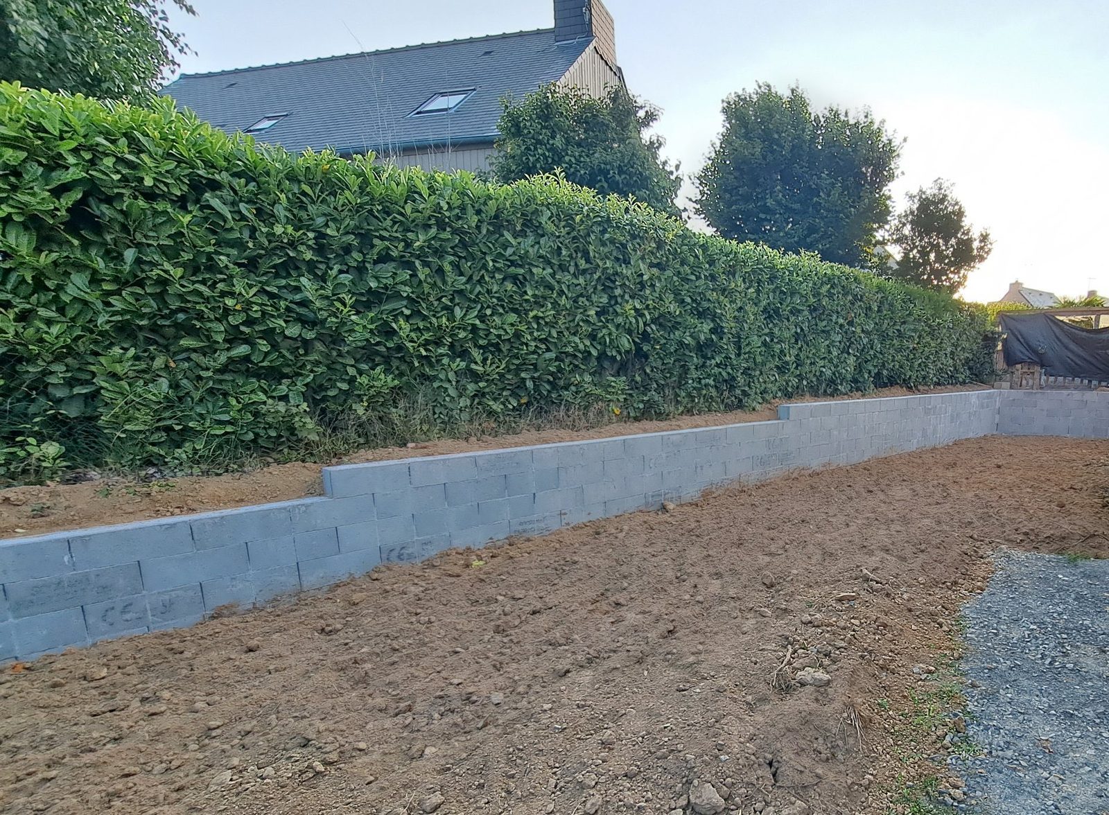 Mur de soutènement en blocs à bancher en limite de jardin, terrain remblayé
